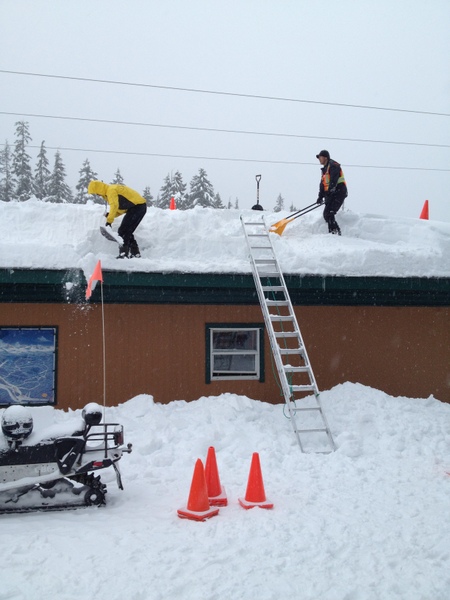 工作人员正忙于铲雪，要不这屋顶要垮了。
